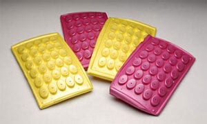 Four pink and yellow plastic buttons on a table.
