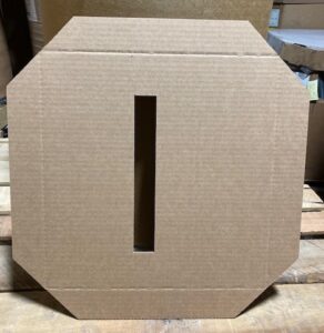 A cardboard box with the letter i cut out of it.