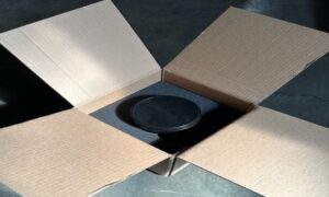 A black plate sitting in the middle of an open box.